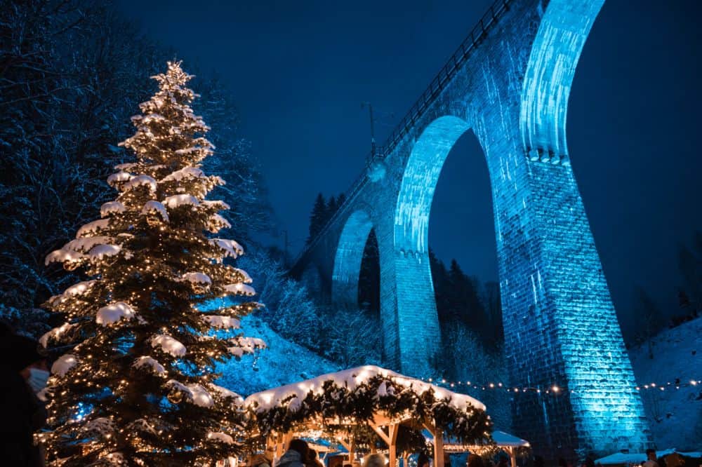 Christmas tree in front of the blue-lit railway viaduct